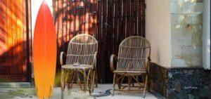 urf camp in Kuta Lombok with surfboard and rattan chairs in a tropical courtyard setting