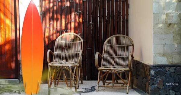 urf camp in Kuta Lombok with surfboard and rattan chairs in a tropical courtyard setting