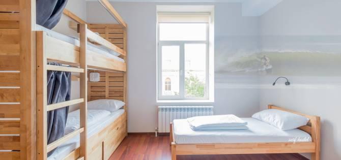 Minimalist surf hostel dorm room in Kuta Lombok with wooden bunk beds and natural light, designed for surfers and budget travellers.